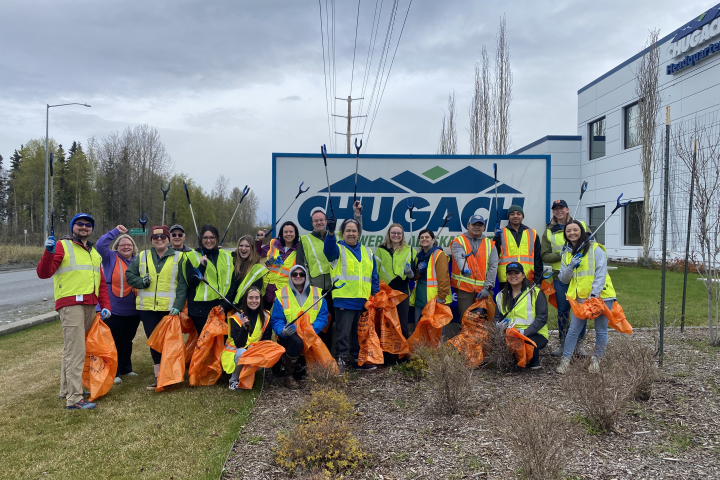 Employees in hi-vis vests pose by the Chugach sign with trash picker tools and orange Citywide Cleanup garbage bags.